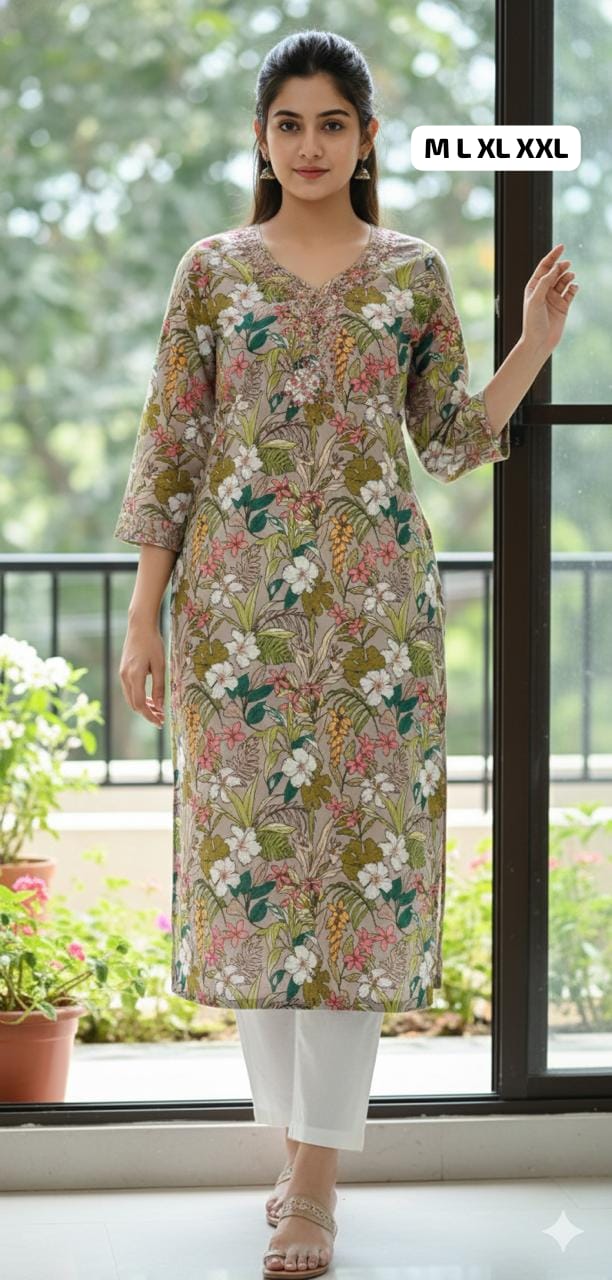 Woman wearing floral beige kurti with 3/4 sleeves and white pants, standing indoors by window