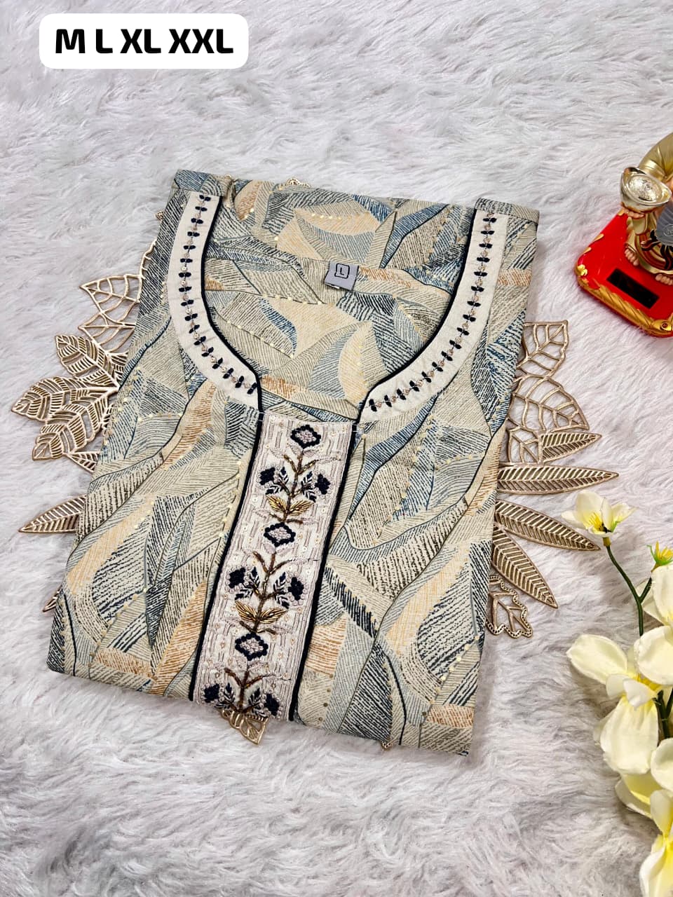 Folded beige and blue patterned kurti with embroidered neckline on white fur background, sizes M to XXL