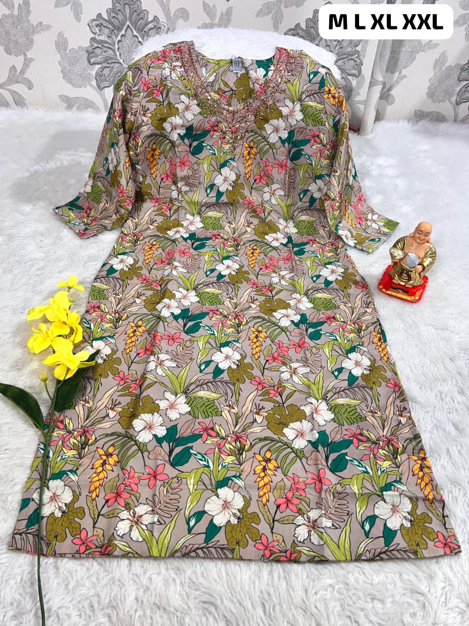 Floral print women's kurti with V-neck and 3/4 sleeves displayed on white furry surface, sizes M to XXL