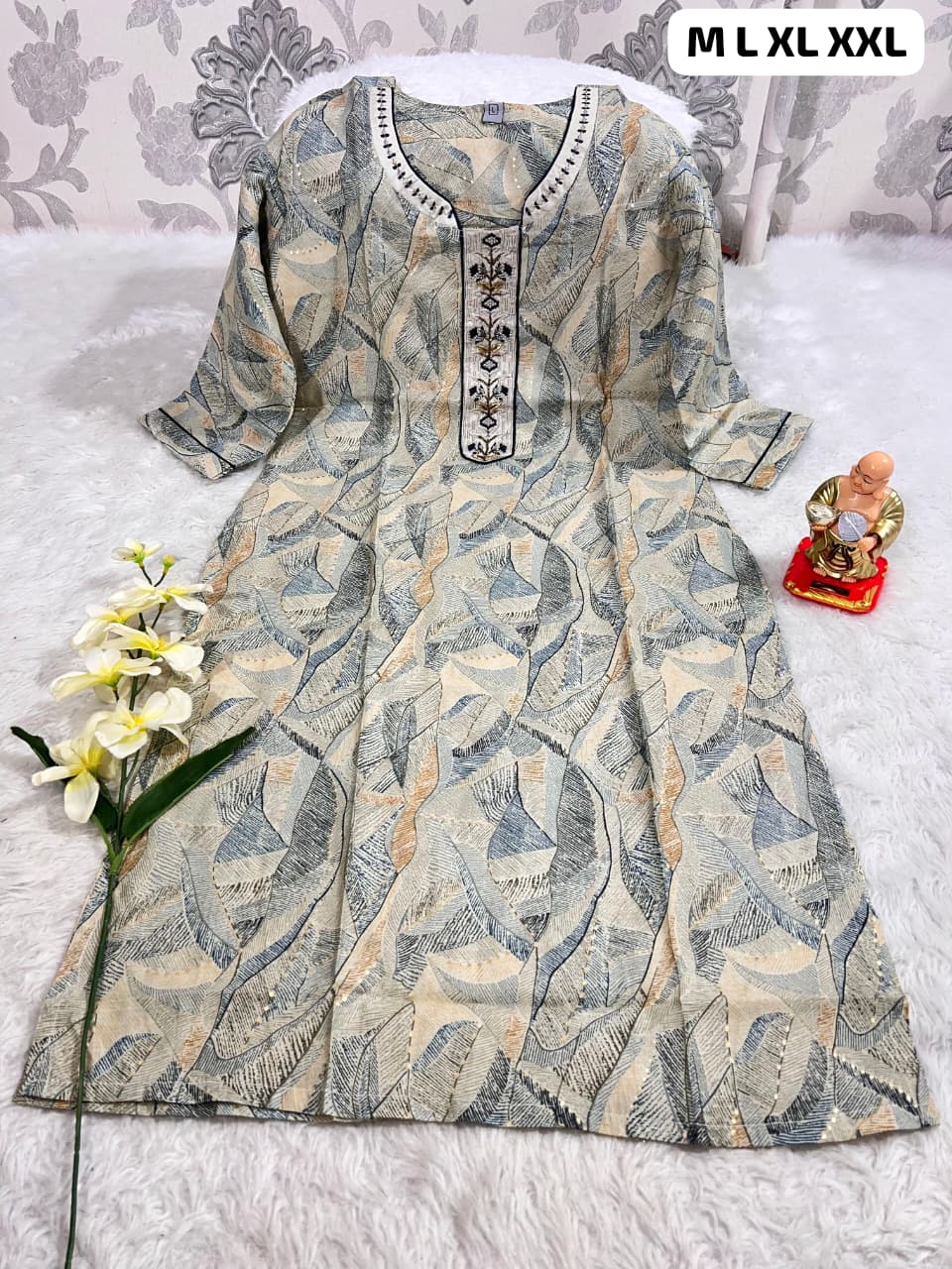 Beige and blue abstract printed kurti with embroidered neckline, displayed on white fur background with flower and Buddha statue